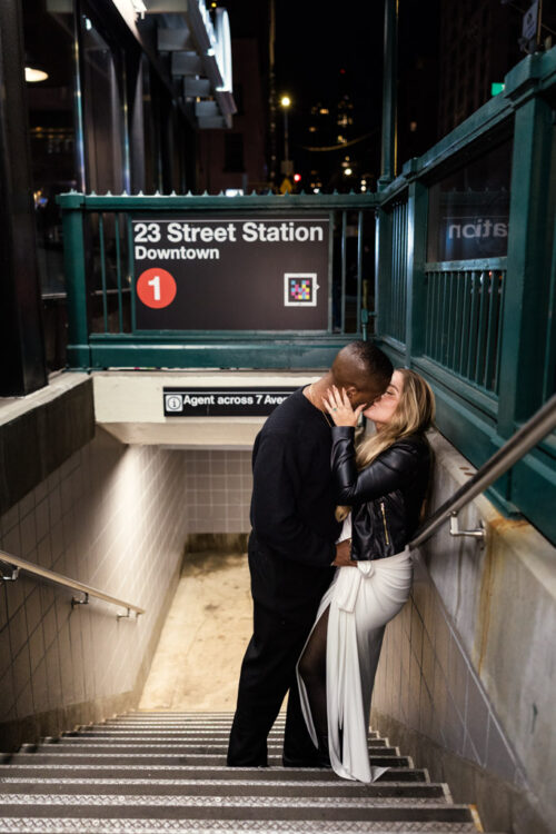 Engaged couple kisses at the entrance of 23rd Street subway station in New York City at night