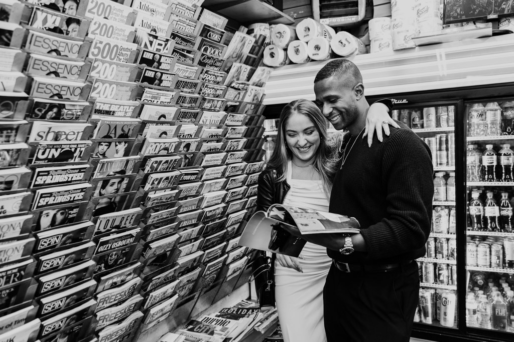 Black and white photo of happy engaged couple browsing magazines together in a New York City bodega