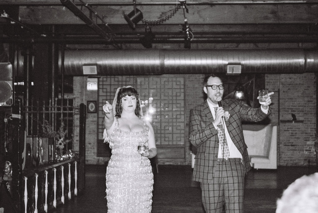 Black and white photo of newlyweds giving a speech during their Salvage One wedding reception