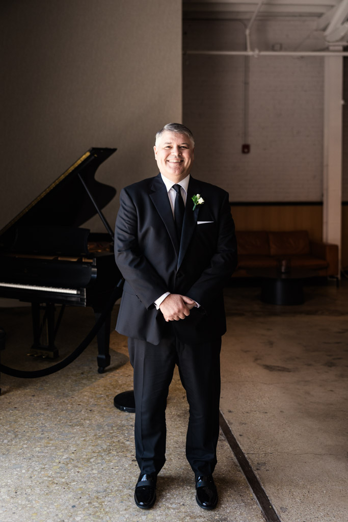 Portrait of happy groom standing beside a grand piano inside Sarabande Chicago