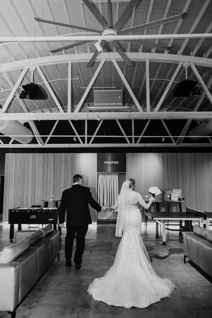 Black and white photo of bride and groom holding hands and walking in a room inside Sarabande Chicago