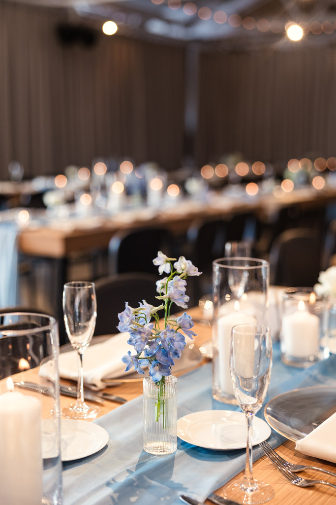 Guest tables set with blue flowers, candles, and glassware for Sarabande Chicago wedding celebration