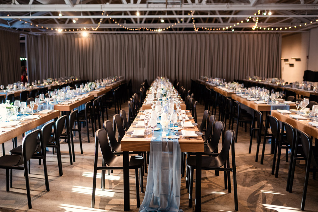 Long banquet tables set for wedding reception with black chairs and soft lighting inside Sarabande Chicago