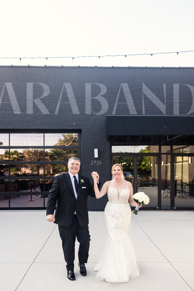 Smiling bride and groom holding hands outside Sarabande Chicago
