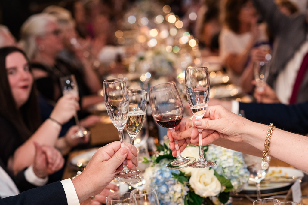Guests clinking glasses in a toast at a festive dinner table adorned with flowers and candles, during wedding reception at Sarabande Chicago