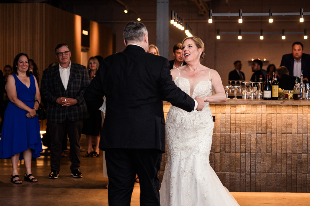 Bride and groom dance together at their Sarabande Chicago wedding reception with guests watching and smiling