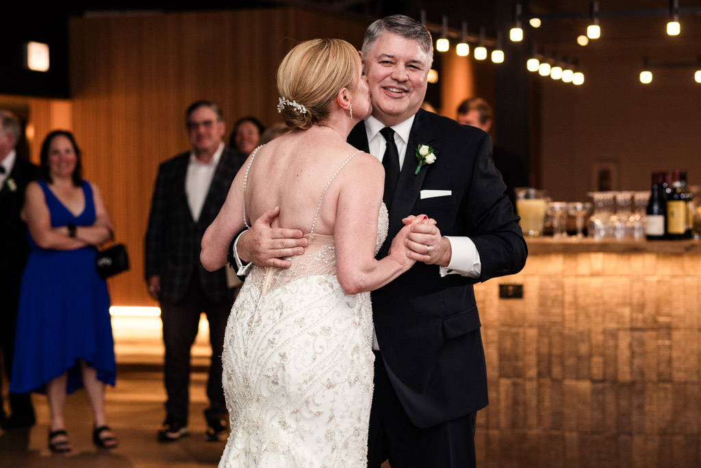 Bride kisses groom's cheek during their first dance at their Sarabande Chicago wedding celebration