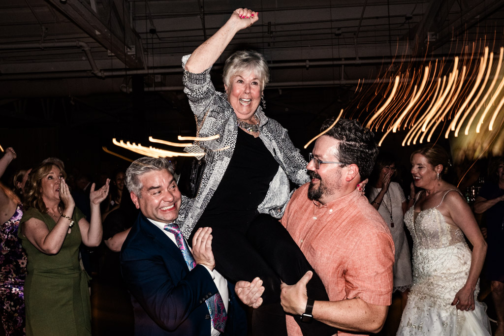 Two men lift a woman on the dance floor during wedding reception at Sarabande Chicago