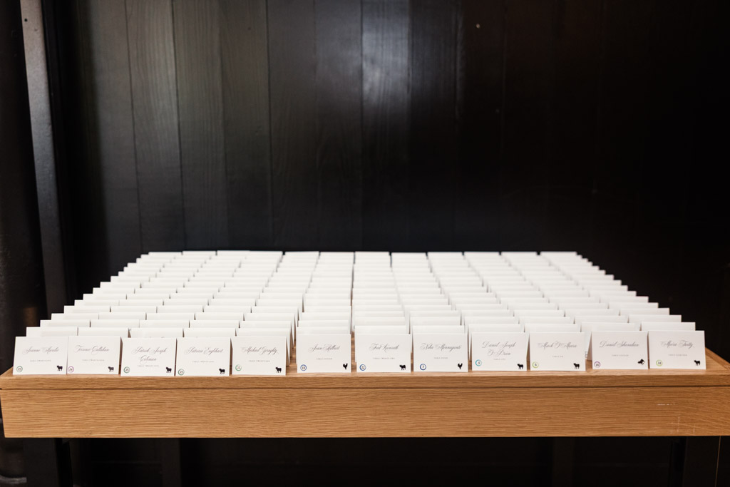 Rows of white, folded place cards arranged on a wooden table against a black background for Sarabande Chicago wedding reception
