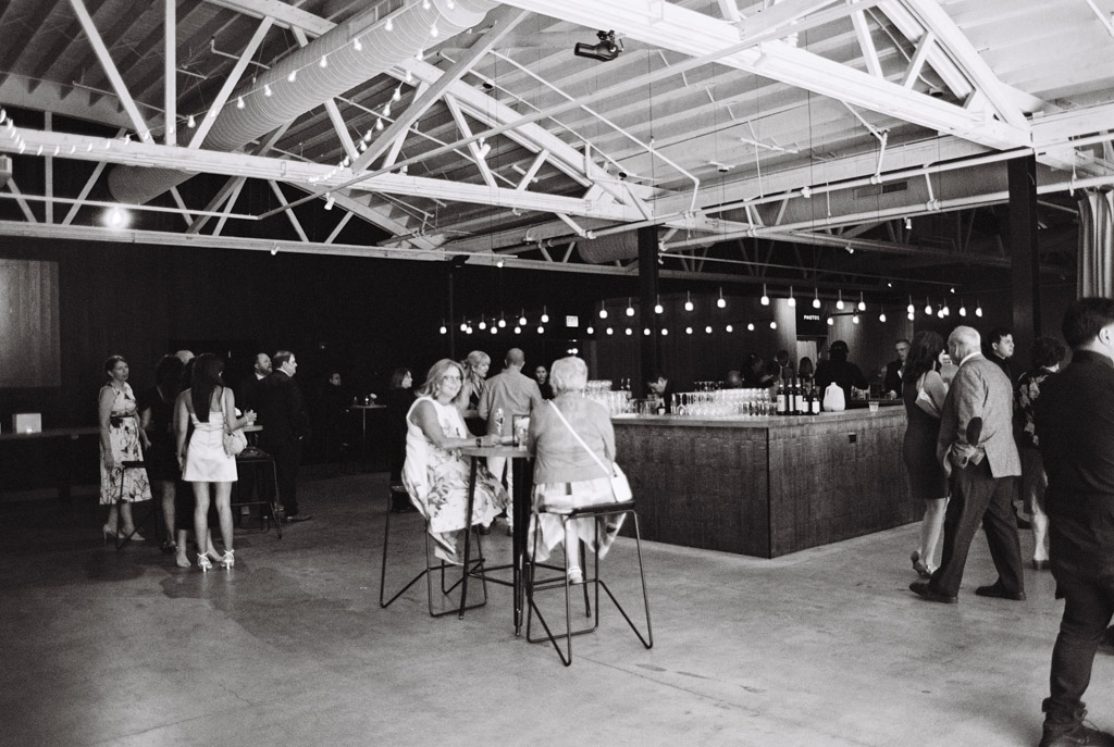 Guests mingle and sit around a bar area inside Sarabande Chicago, featuring exposed beams