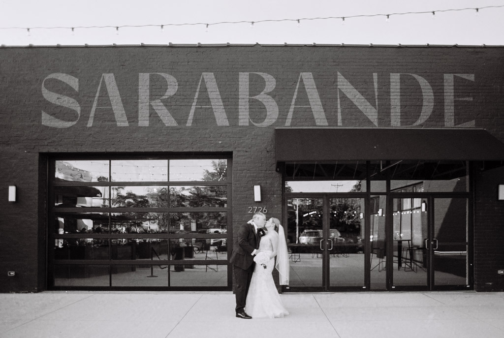 Black and white photo of bride and groom kissing outside Sarabande Chicago