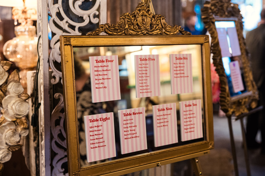 Gold-framed mirror displaying printed table seating cards for a Salvage One wedding celebration
