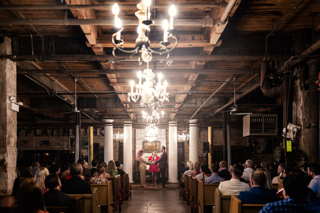 A couple stands holding hands during their Salvage One wedding ceremony