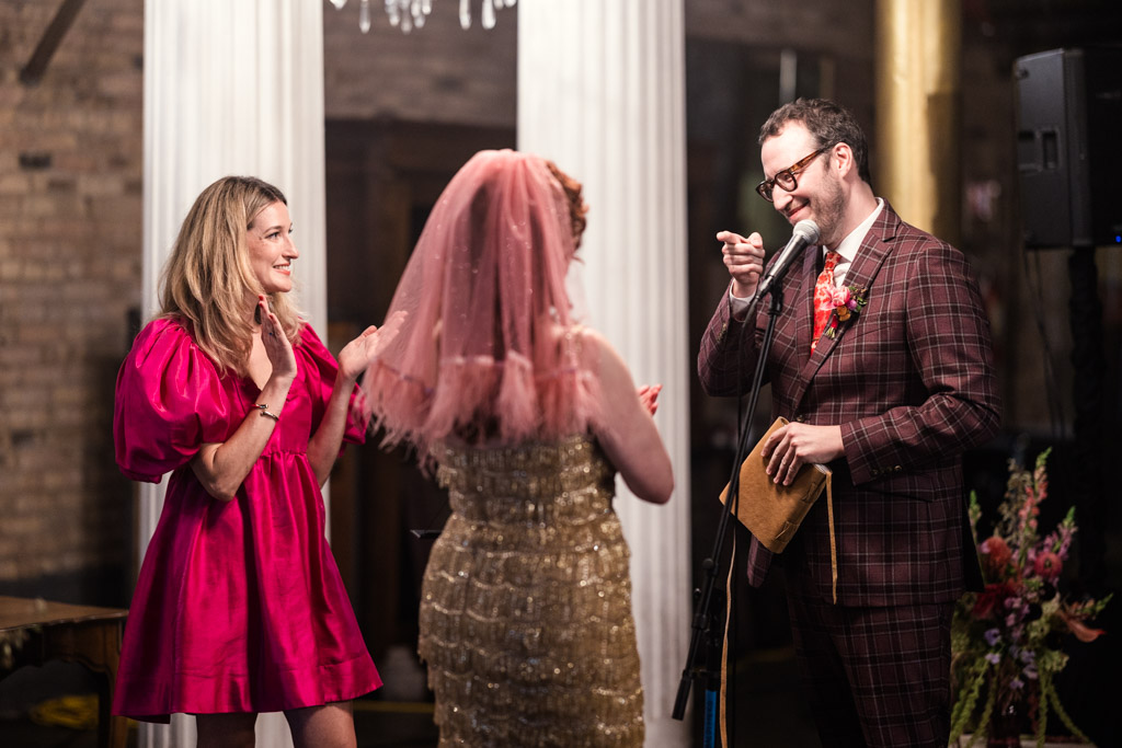 At their Salvage One wedding ceremony, the groom points playfully at the bride while speaking