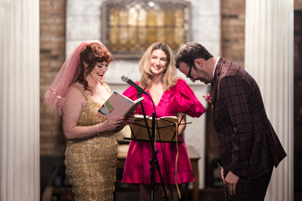 Groom laughs while the bride reads her vows during the Salvage One wedding ceremony
