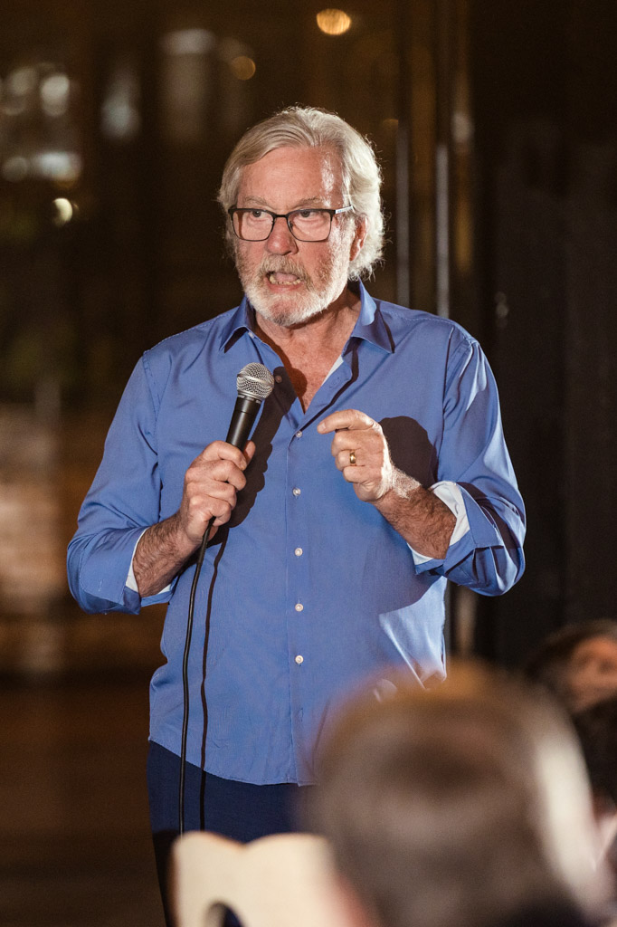 Guest with gray hair and glasses gives a speech during Salvage One wedding reception