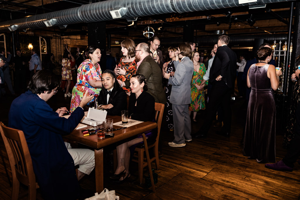 Guests in formal attire mingle and chat at a Salvage One wedding reception