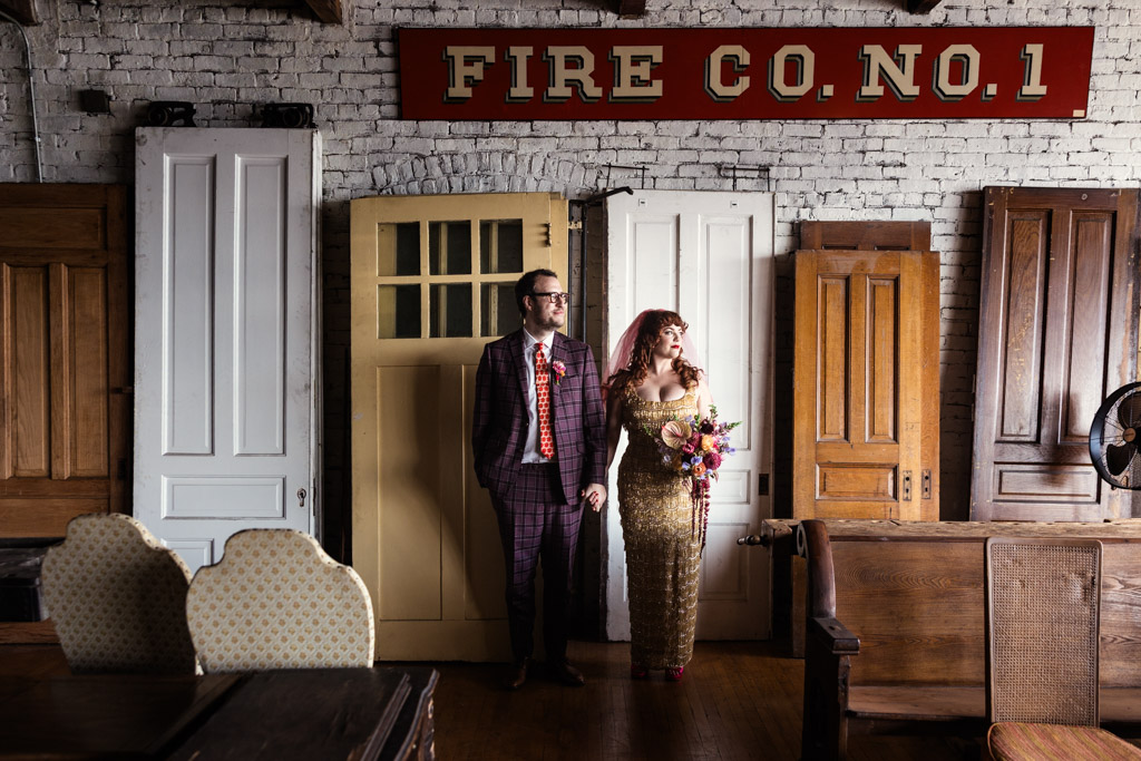 Portrait of bride and groom holding hands in front of vintage doors under a 