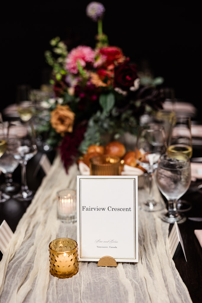 Guest table setting with flowers, candles, and a place card on a cream table runner for wedding reception at The Arbory Chicago