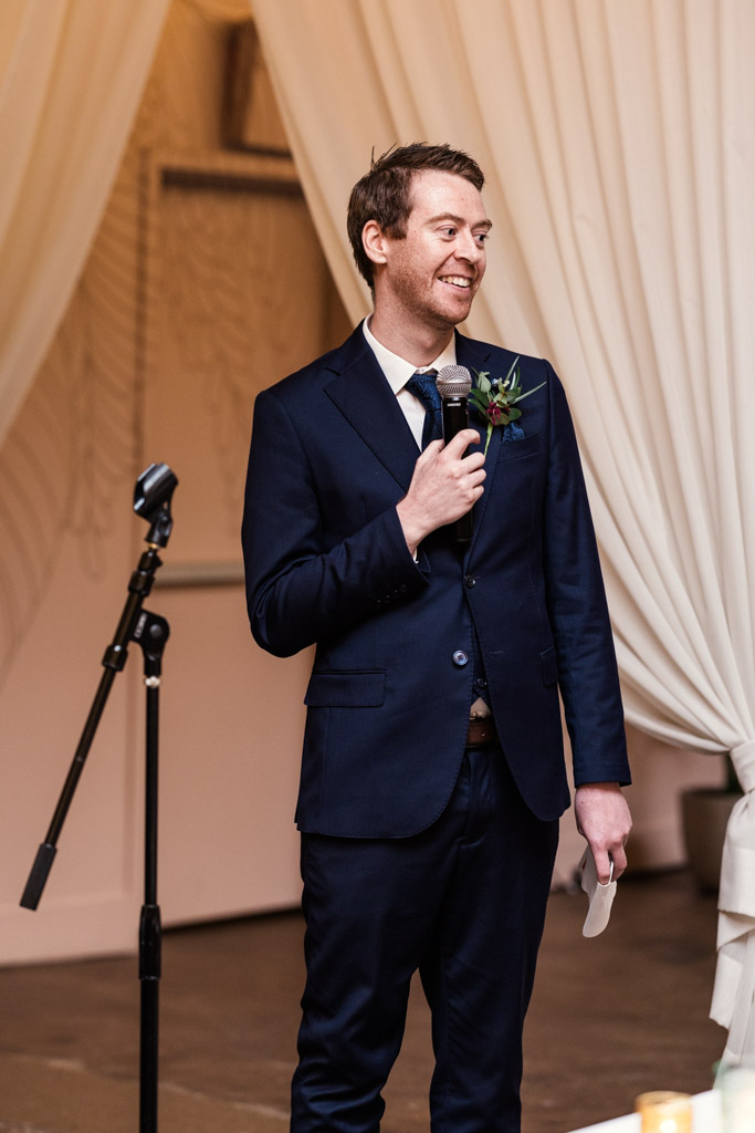 Best Man in a navy suit gives speech during wedding reception at The Arbory Chicago