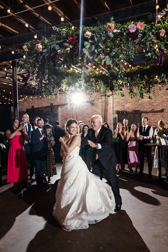 Bride and her father dance during her wedding reception at The Arbory Chicago, surrounded by cheering guests