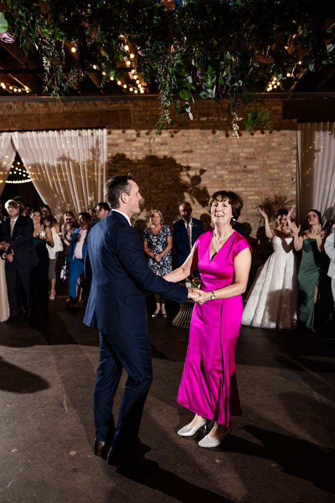 Groom and his mother dance together at his wedding reception at The Arbory Chicago, as guests watch and clap in the background