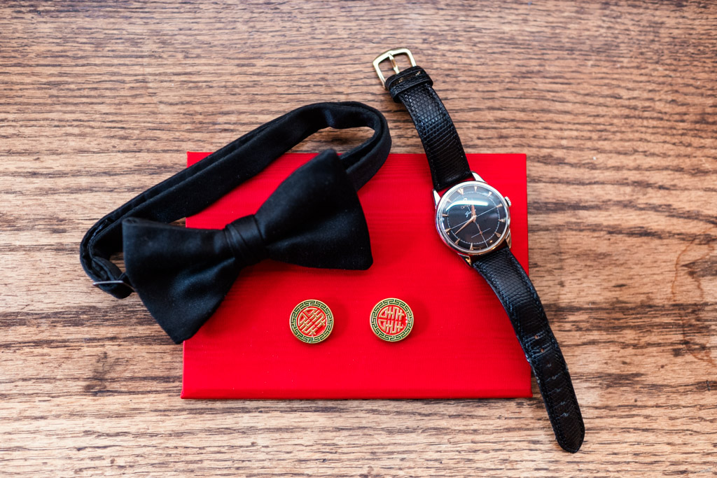 Groom's bow tie, watch, and red cufflinks on a red vow book for wedding celebration at The Joinery in Chicago