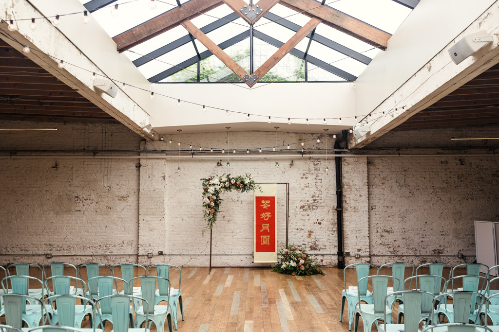 Wedding ceremony space at The Joinery with floral arch and a red Chinese banner
