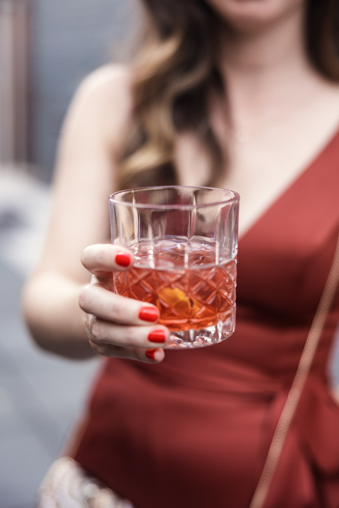Woman in a red dress holding a cocktail with orange peel during wedding reception at The Joinery in Chicago