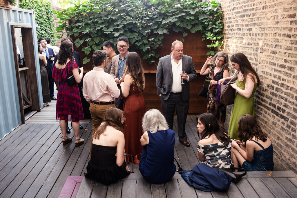 Guests socializing at an outdoor gathering in a walled courtyard with lush greenery at the Joinery in Chicago