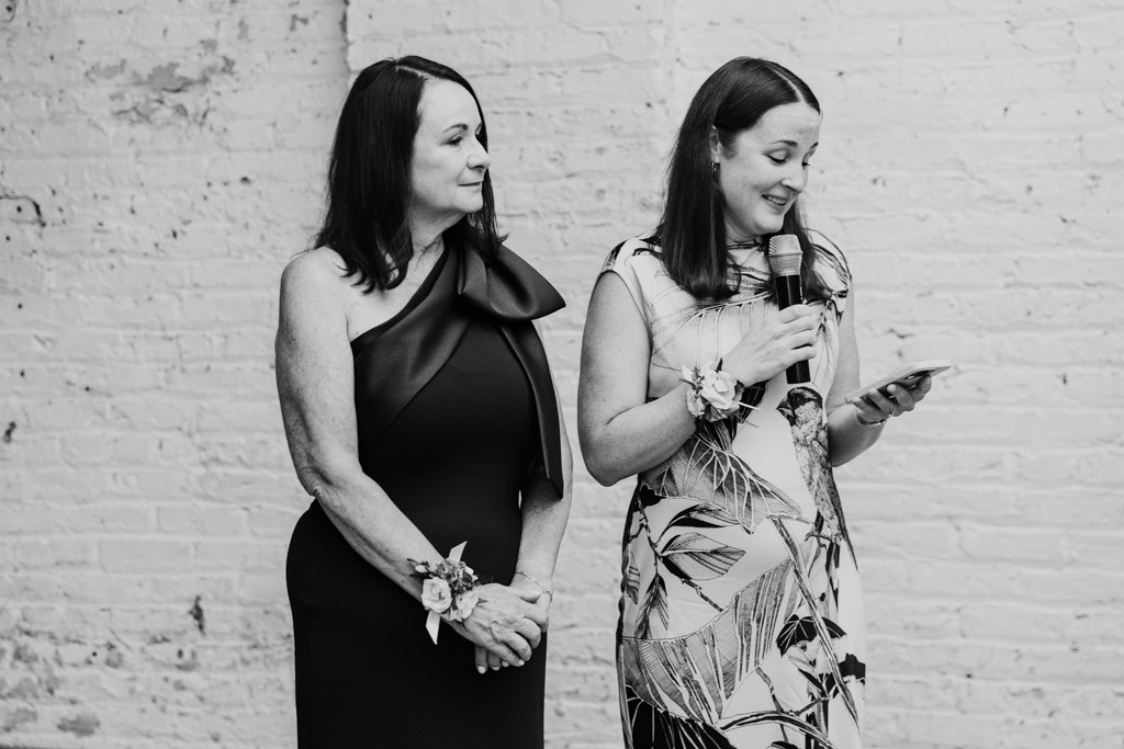 Black and white photo of two women giving a speech during wedding reception at The Joinery in Chicago