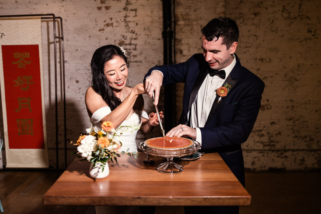 A bride and groom happily cutting a cheesecake together at their Joinery wedding reception