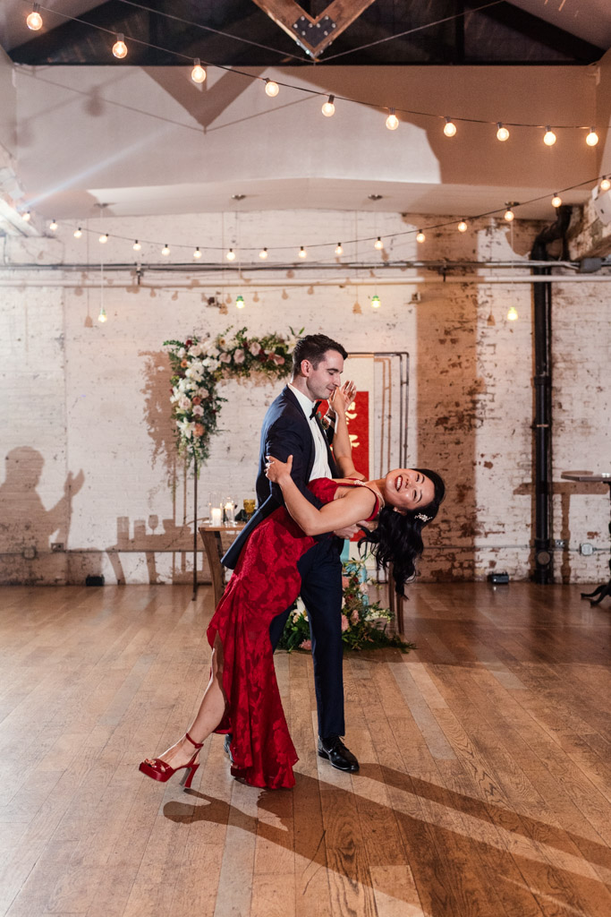 Newlywed couple dances under string lights in The Joinery's wedding reception space