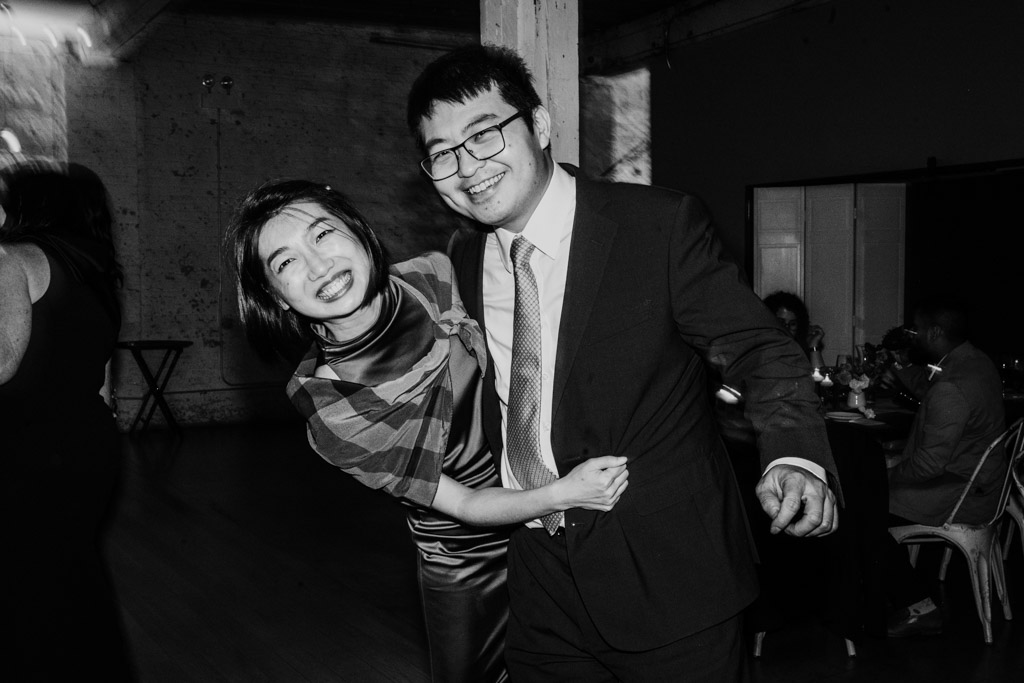 Black and white photo of smiling woman and man in formal attire dancing together during wedding reception at The Joinery