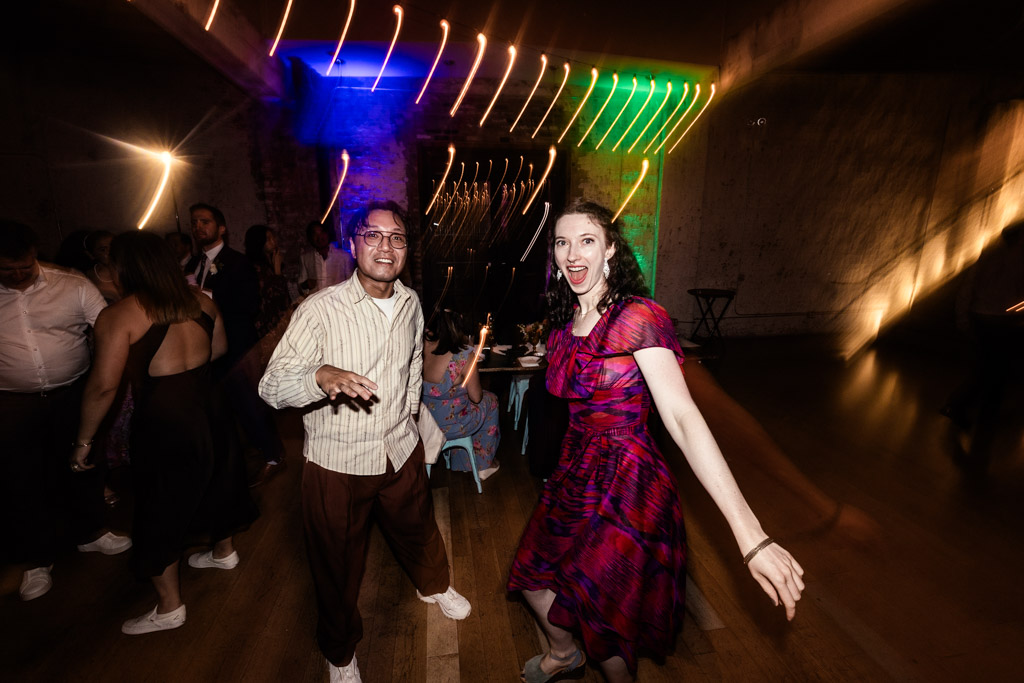Two guests dancing energetically at a party with colorful lights and blurred motion effects during wedding reception at The Joinery