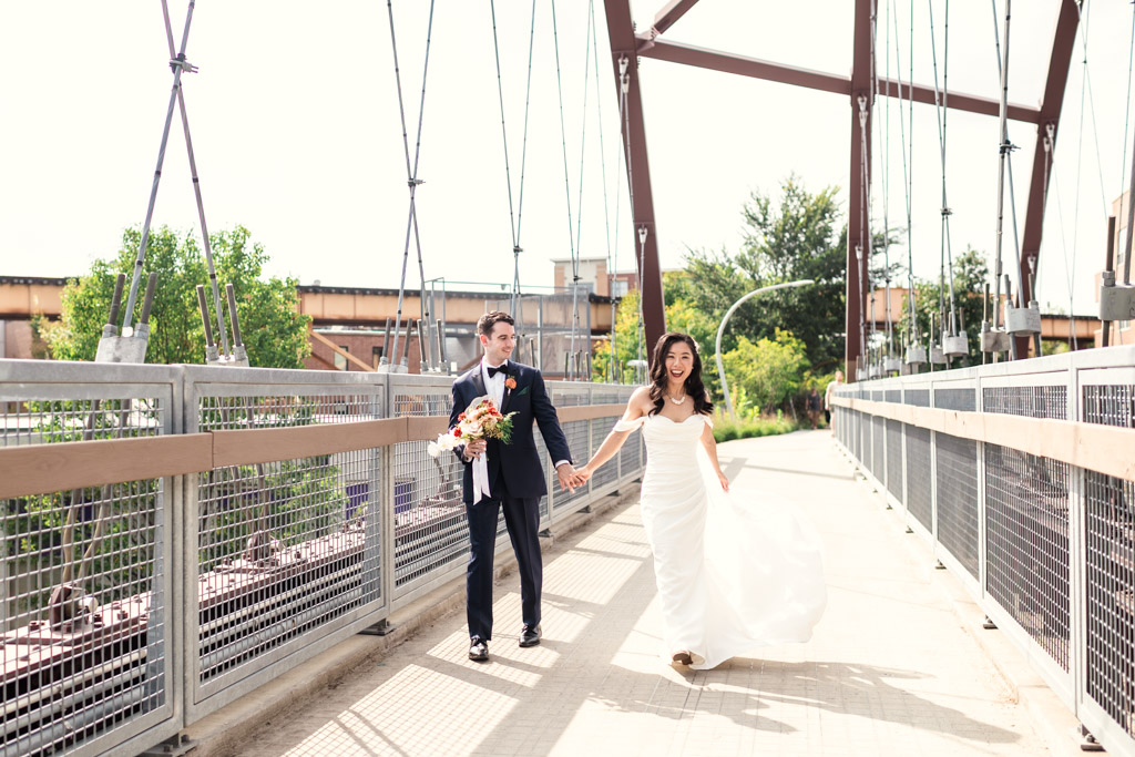 Bride and groom holding hands and smiling as they walk across the 606 Bridge in Wicker Park