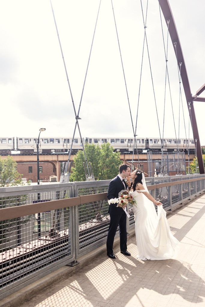 Bride and groom kiss on the 606 Bridge in Wicker Park with a CTA train visible in the background