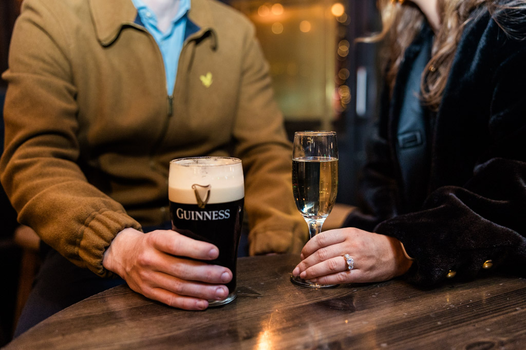 Two people sit at a table, celebrating their Dublin engagement with a pint of Guinness and a glass of sparkling wine.