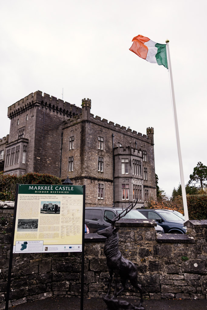 Markree Castle with an Irish flag, informational sign, and a stag statue in the foreground