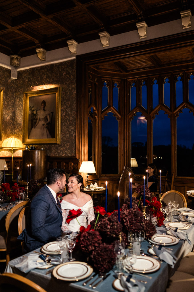 A couple sits closely at an elegant, candlelit dinner table in a grand, ornate room at Markree Castle at night