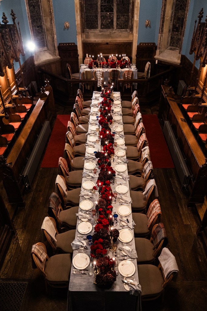 Long banquet table set with red flowers, candles, and place settings inside Markree Castle