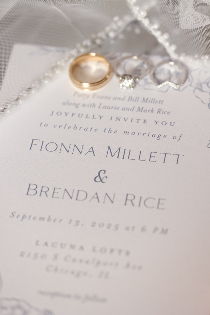 A wedding invitation card with rings placed on top and bride's veil for Lacuna Lofts wedding celebration