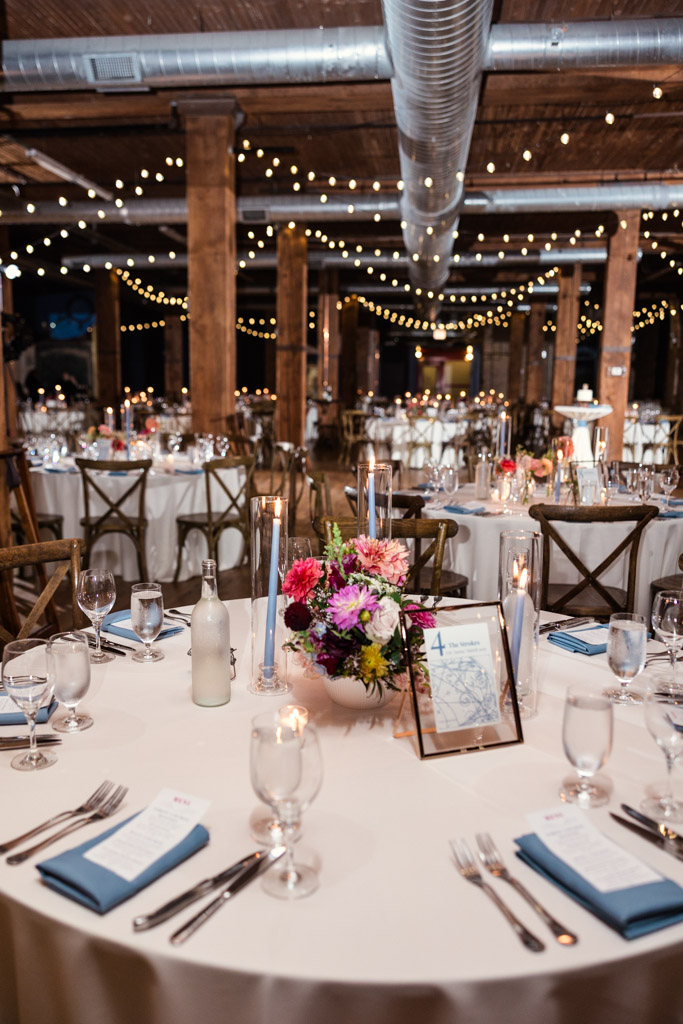 Lacuna Lofts wedding reception space set with round guest tables with floral centerpieces, candles, and string lights