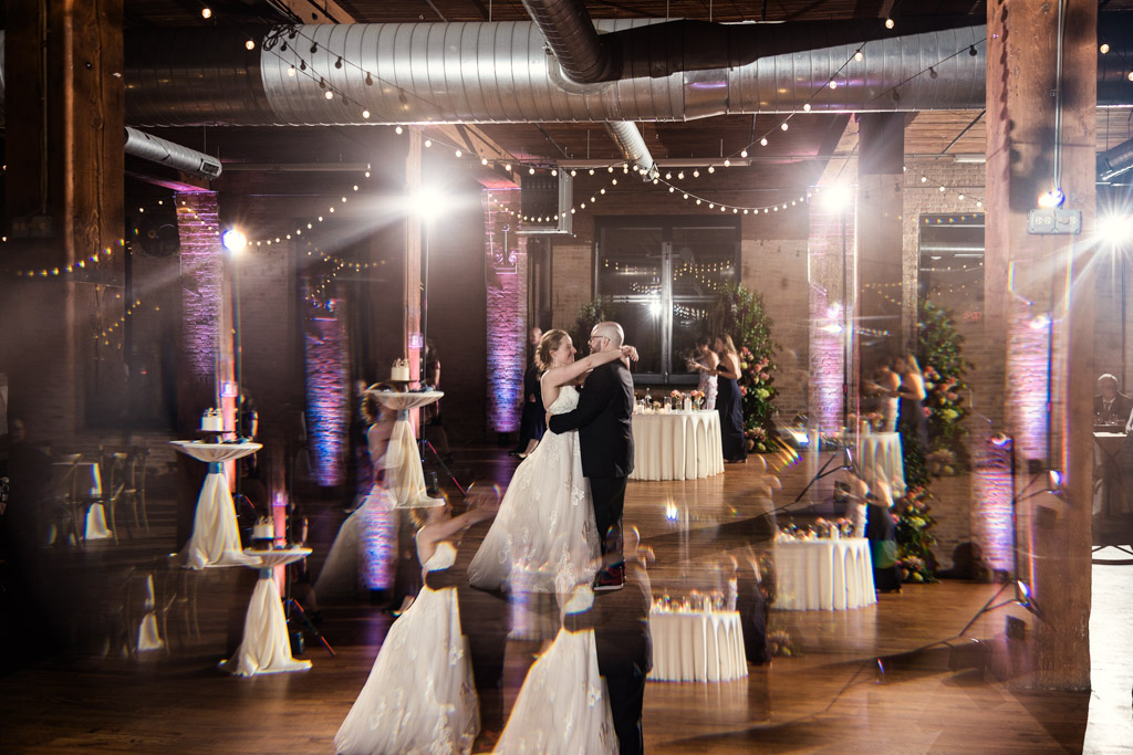 Creative prism photo of bride and groom dancing under string lights in the warmly lit wedding reception space at Lacuna Lofts