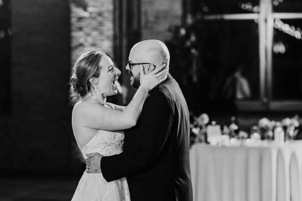 Black and white photo of bride and groom singing together during their first dance at their Lacuna Lofts wedding reception
