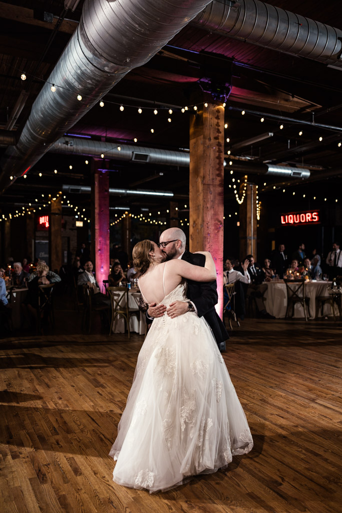 Newlyweds share their first dance in a warmly lit, industrial-style wedding space at Lacuna Lofts