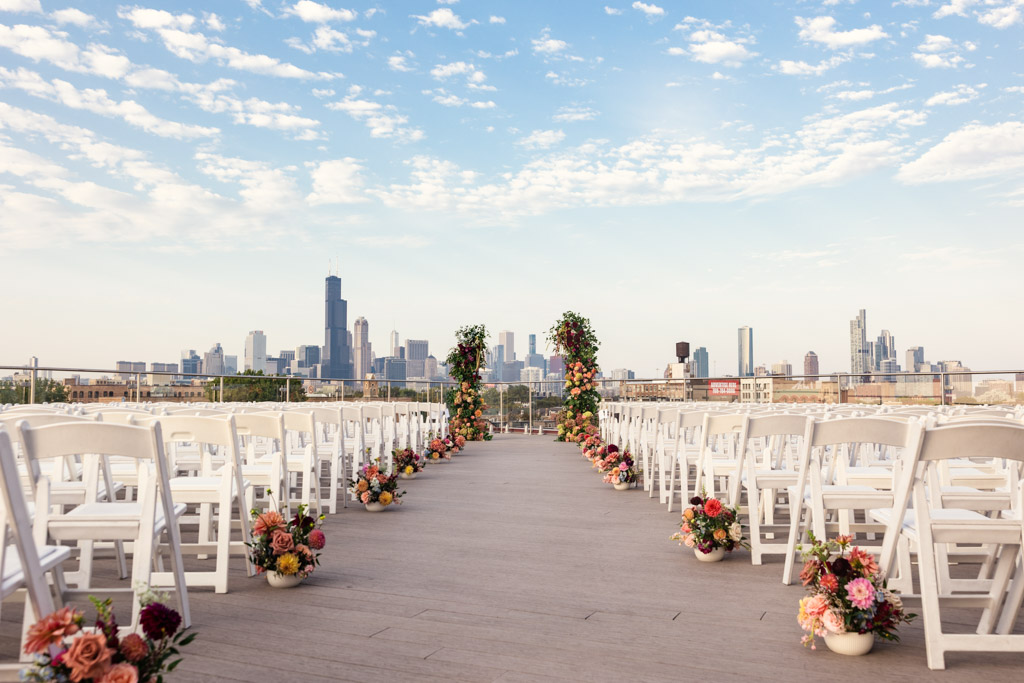 Rooftop wedding ceremony space at Lacuna Lofts with white chairs, floral arrangements, and the Chicago skyline in the background