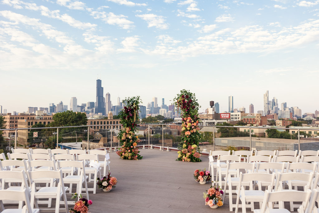 Rooftop wedding ceremony space at Lacuna Lofts with white chairs, floral arrangements, and the Chicago skyline in the background