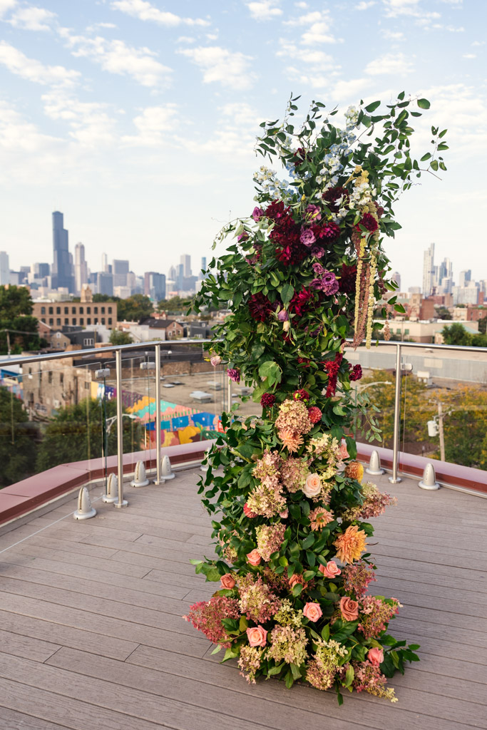 Tall floral decor on the rooftop of Lacuna Lofts with a city skyline in the background under a partly cloudy sky
