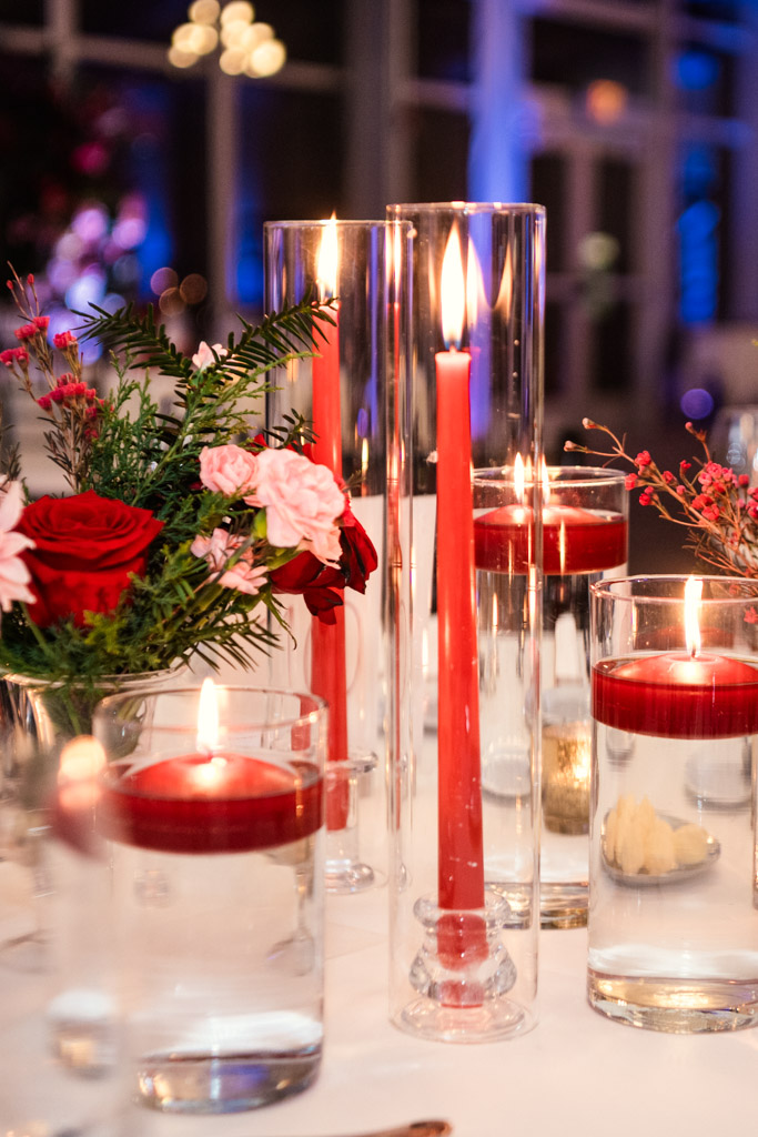 Red candles in tall glass holders and red flowers arranged on a guest table for wedding reception at Lincolnshire Marriott Resort